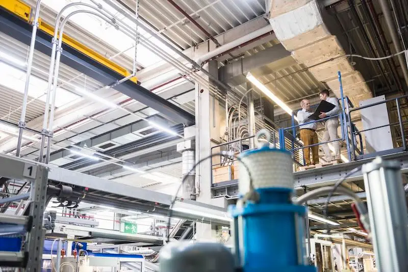 Retro commissioning: The Benefits? Two men talking in factory shop floor